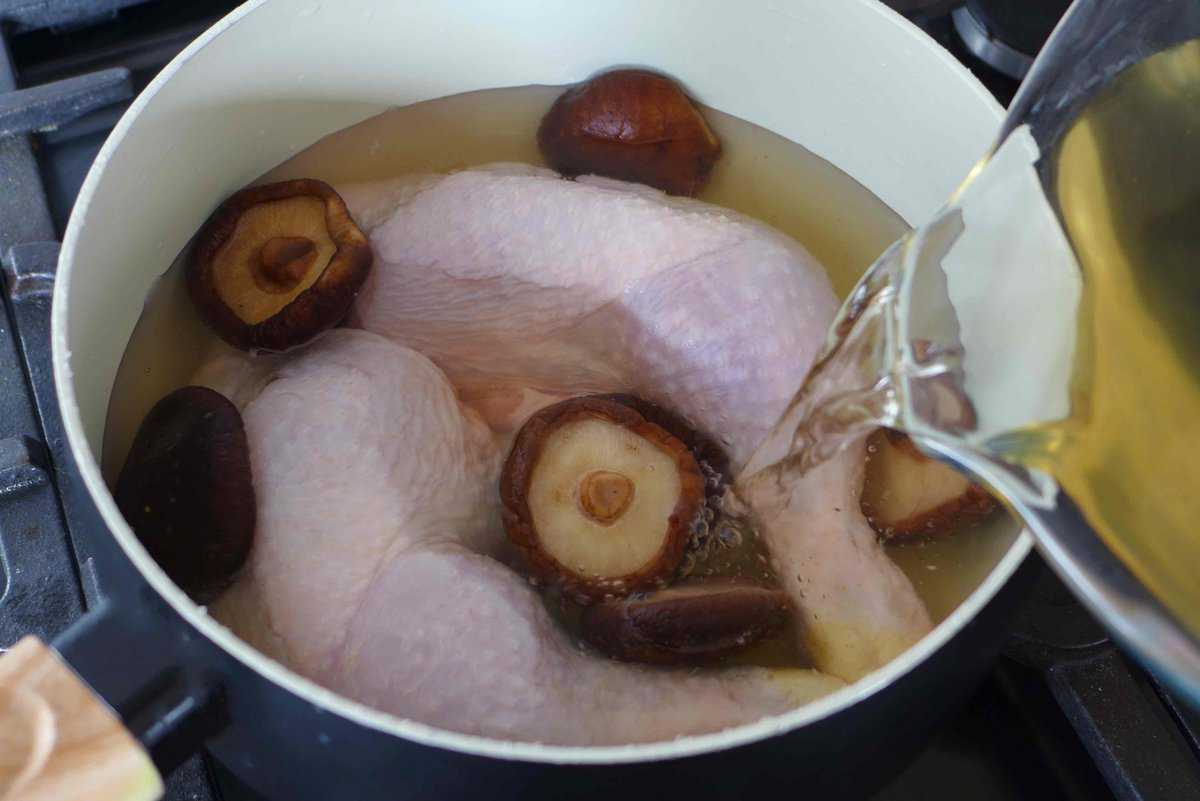pouring mushroom soaking water over chicken legs.