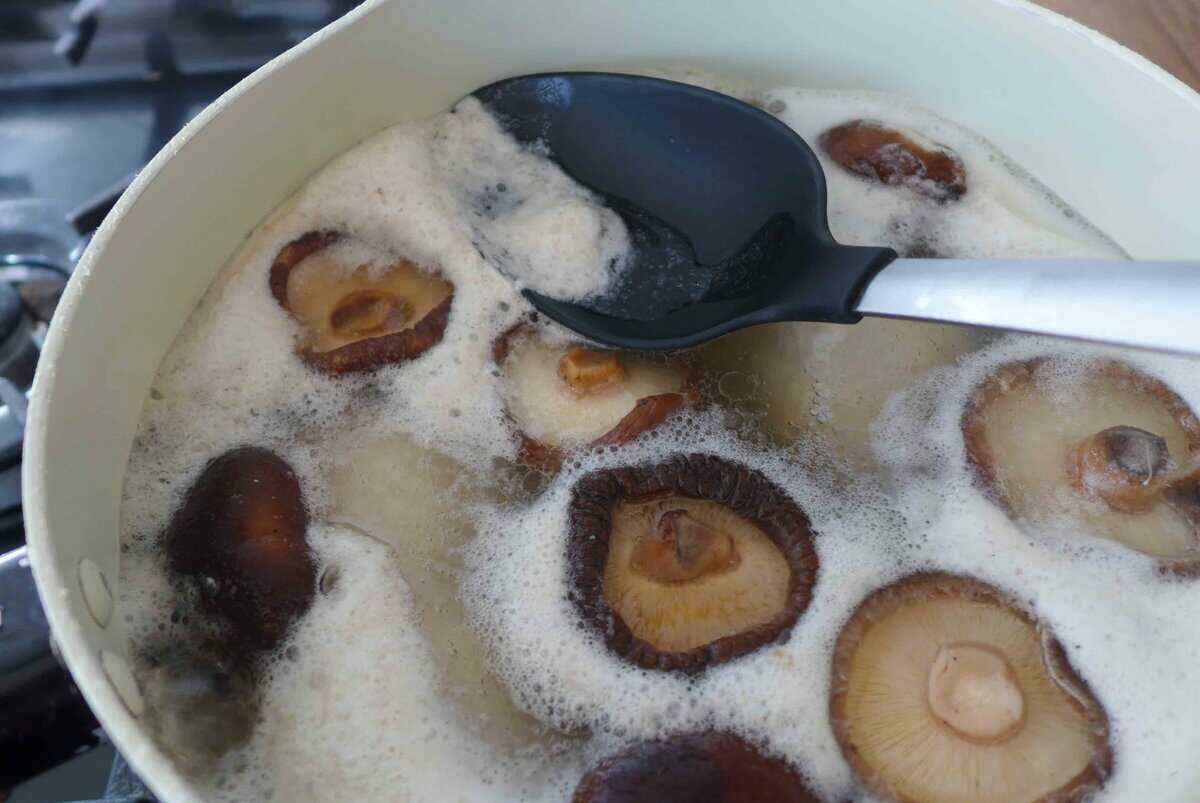 skimming off foam in soup with a spoon.