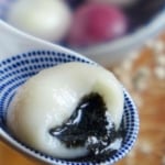 A half eaten white tang yuan with black sesame filling.