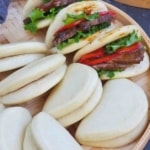 steamed bao buns on a tray with overlay text that says steamed bao buns.