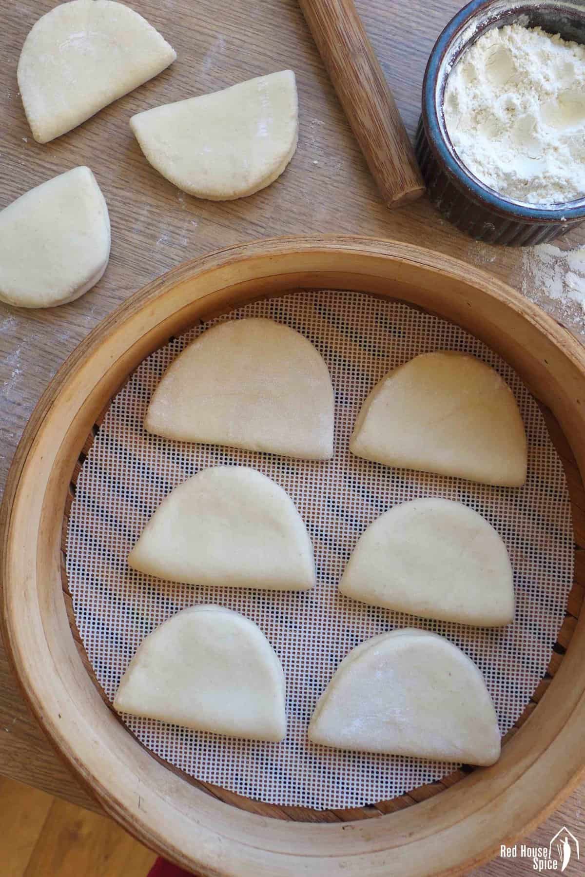 uncooked bao buns in a steamer.