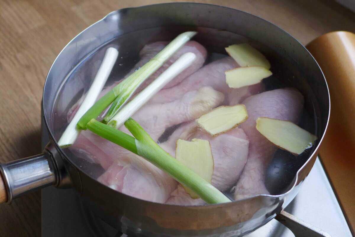 raw chicken drums in water with scallions and ginger.