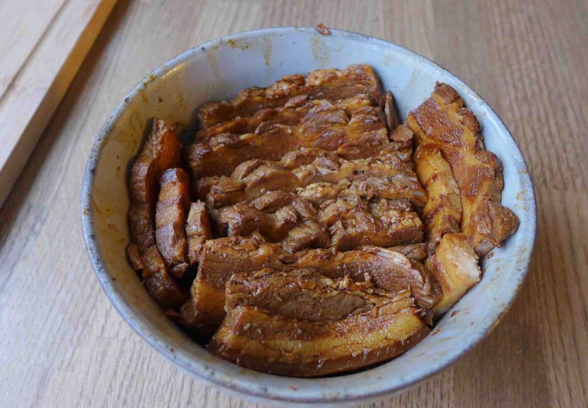 Marinated pork belly slices laid inside a bowl.