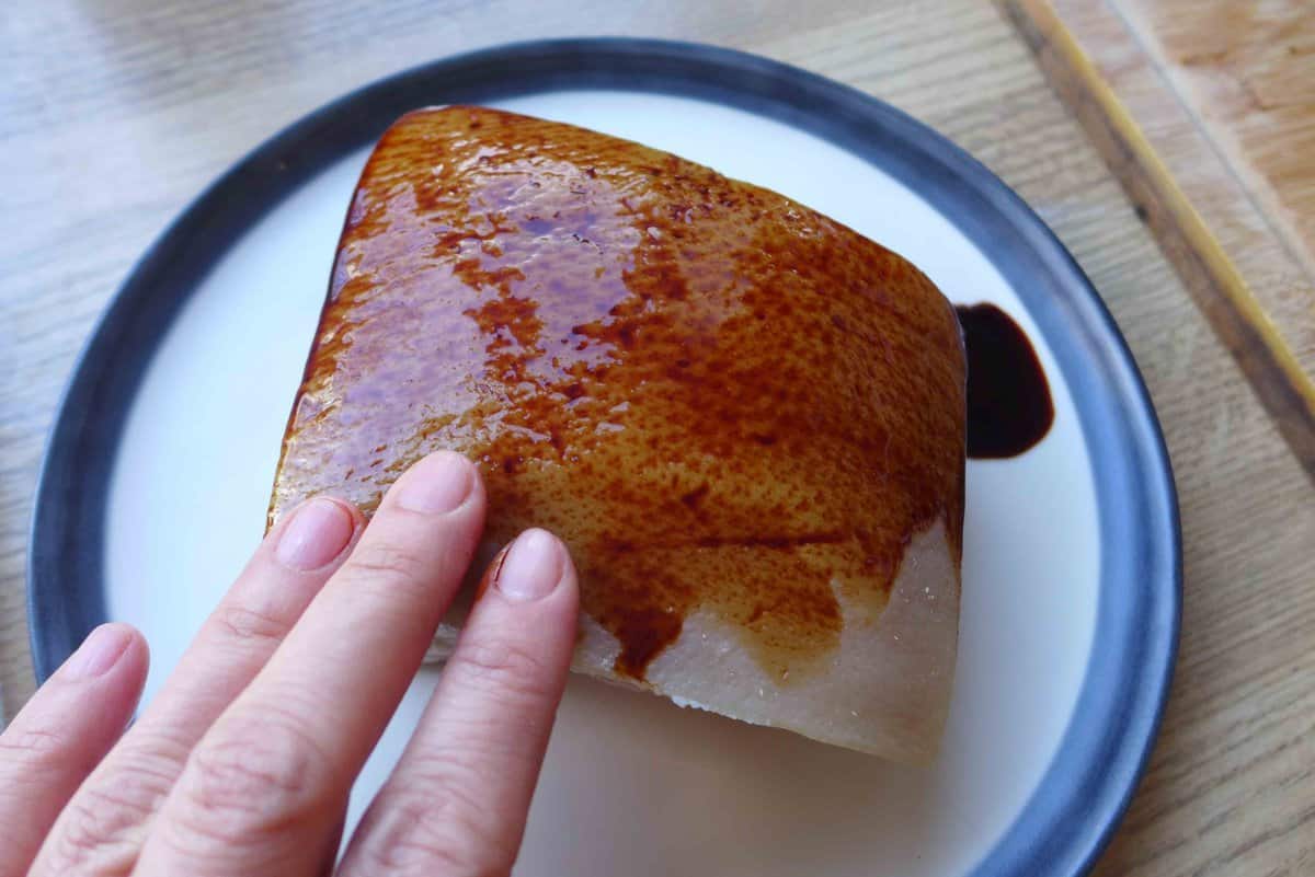 rubbing dark soy sauce over a piece of cooked pork belly.