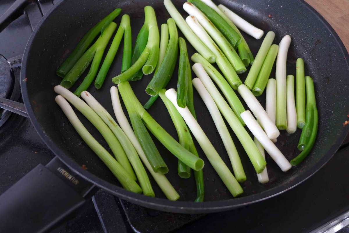 frying scallions in a pan.