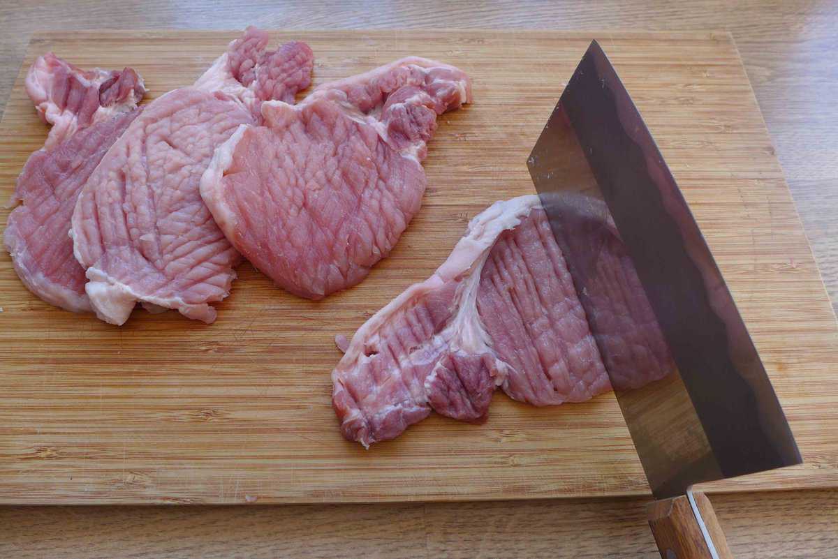 pounding pork chops with the back of a cleaver.