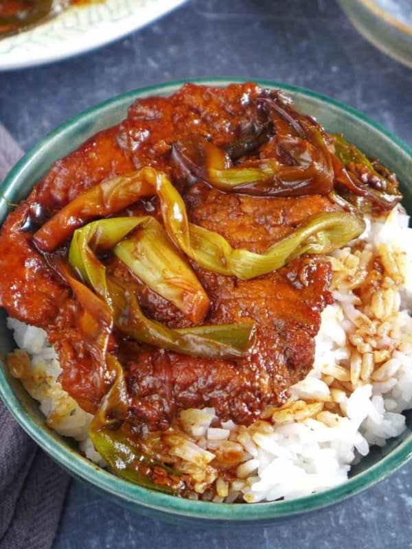 scallion pork chop over a bowl of rice.