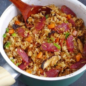 Chinese sausage rice with carrots and mushroom in a saucepan.