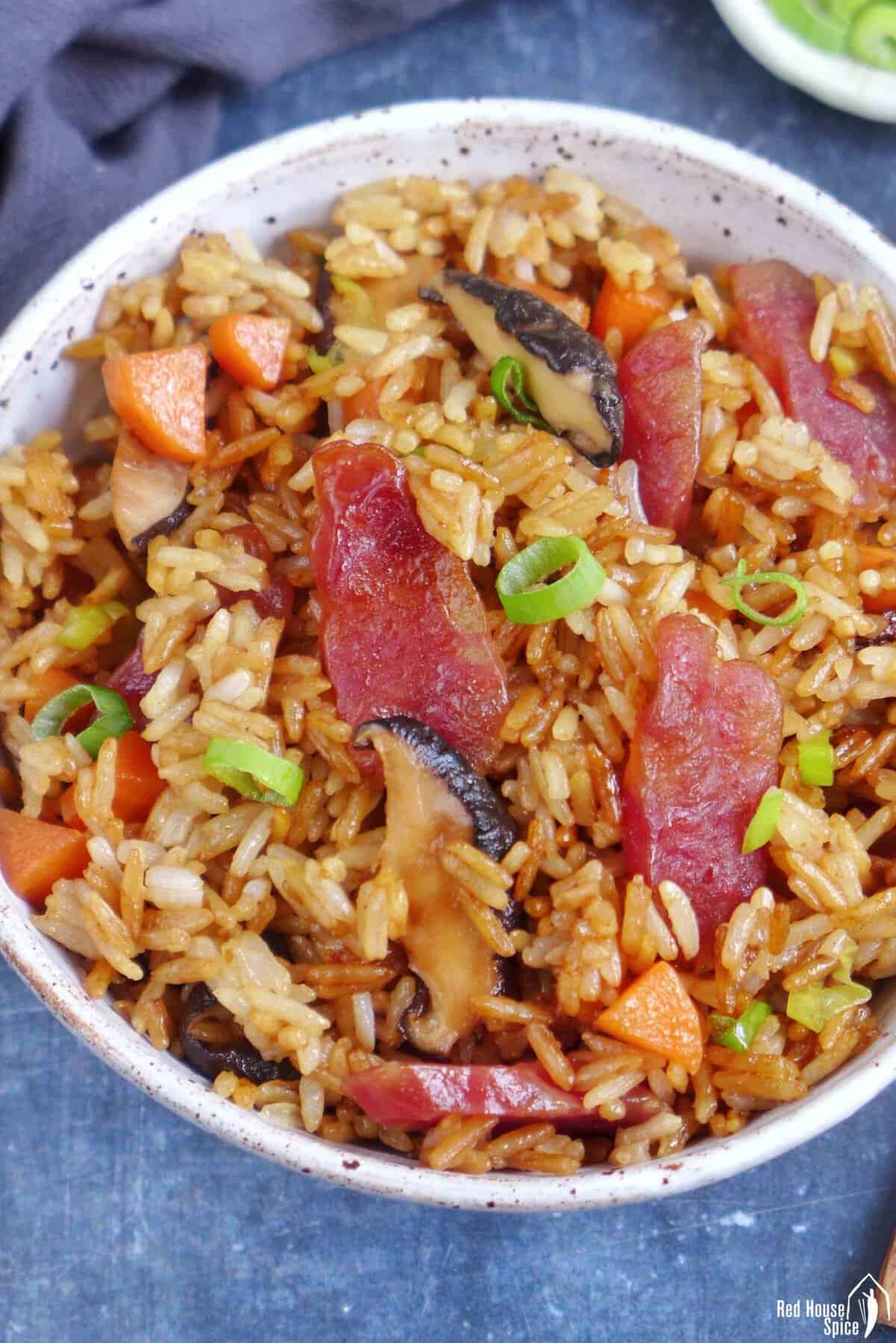 Chinese sausage rice with carrots and mushroom in a bowl.