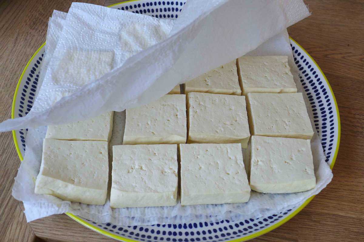 Drying sliced tofu with kitchen paper.