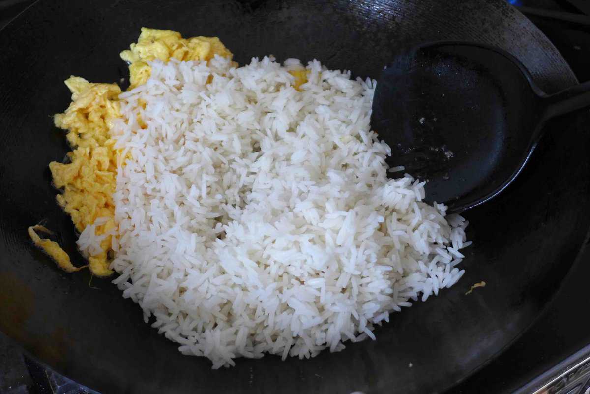 adding cooked rice to scrambled eggs.