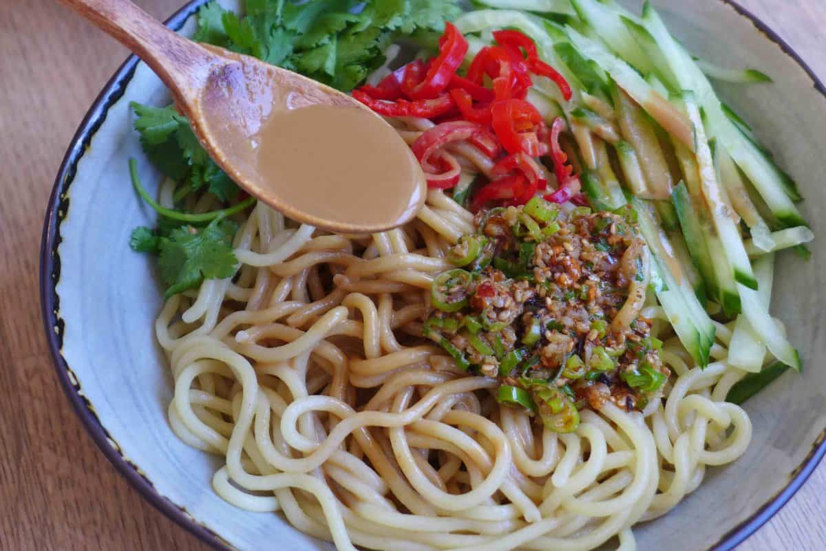 Adding sesame sauce to noodles and vegetables.