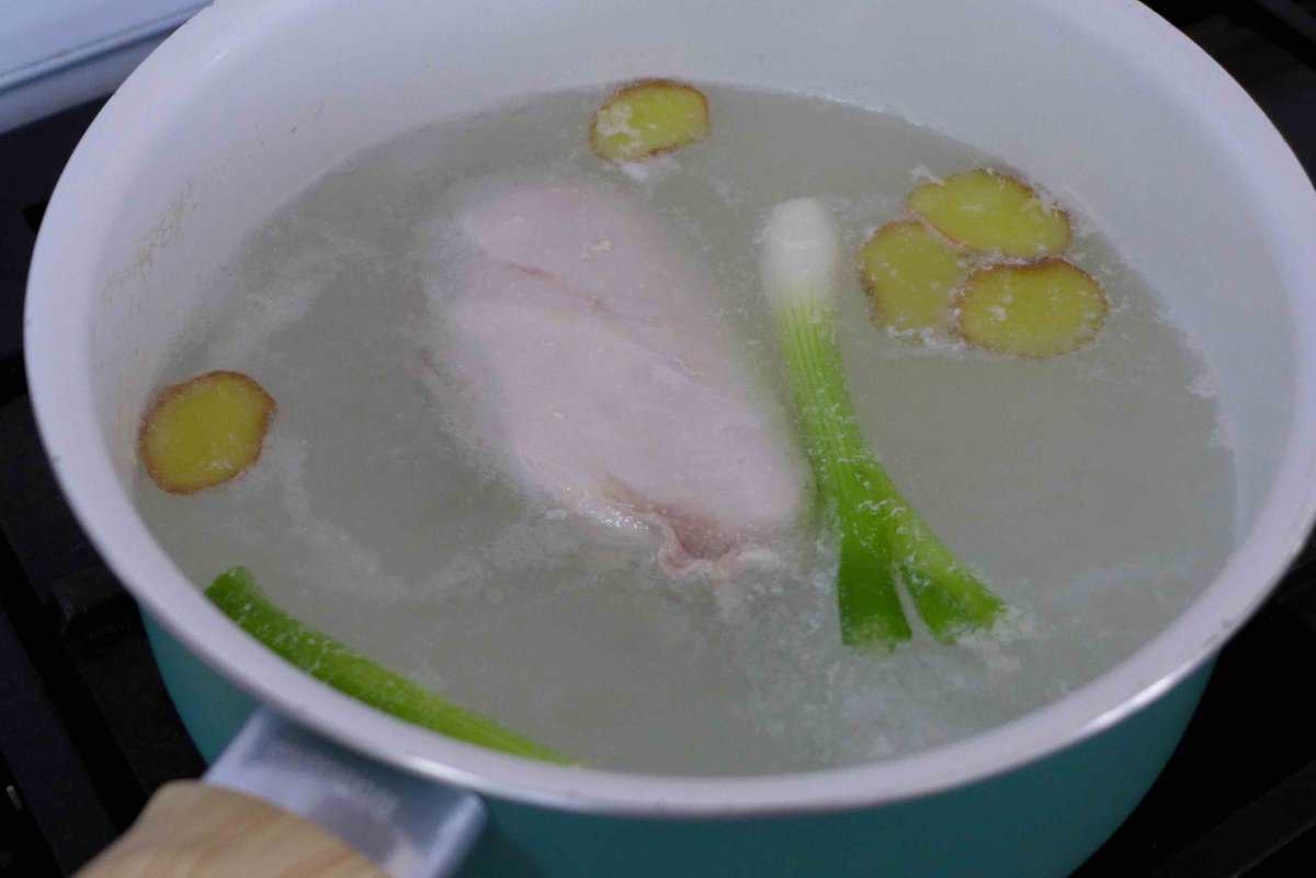 cooking chicken in water with scallions and ginger.
