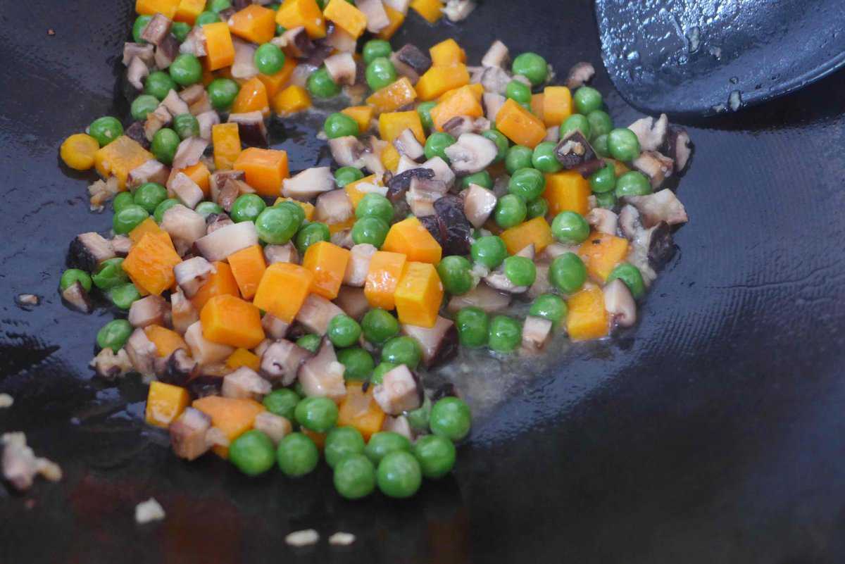 frying peas, carrots and mushrooms in wok