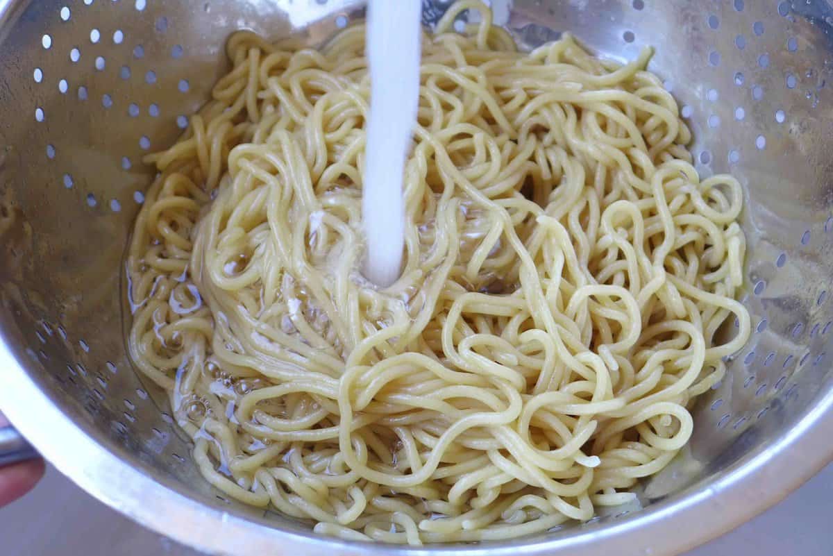 rinsing cooked noodles under running water.