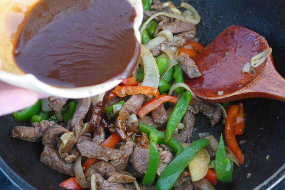 pouring sauce over meat and veggies.