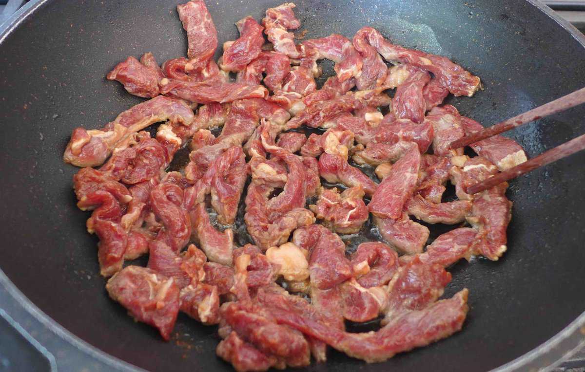 searing beef strips in a wok.