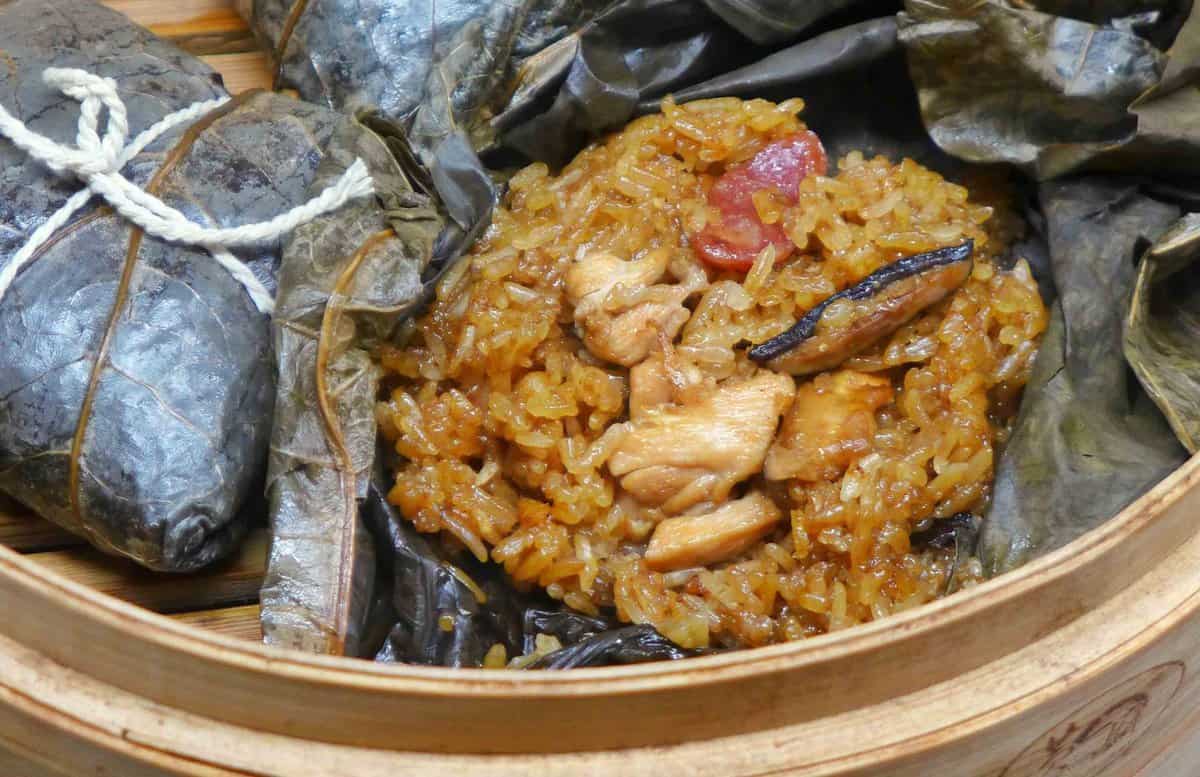 stick rice, chicken, sausage and mushrooms over a lotus leaf.