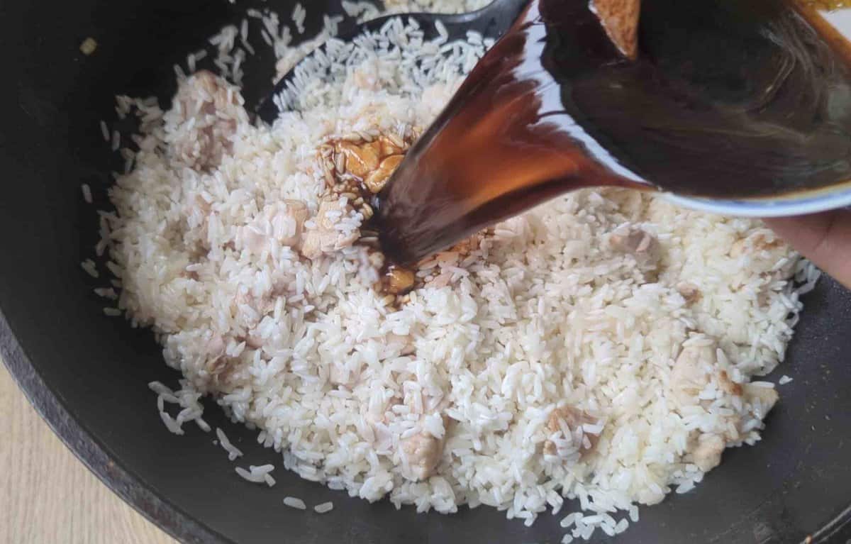 pouring sauce over rice and chicken.