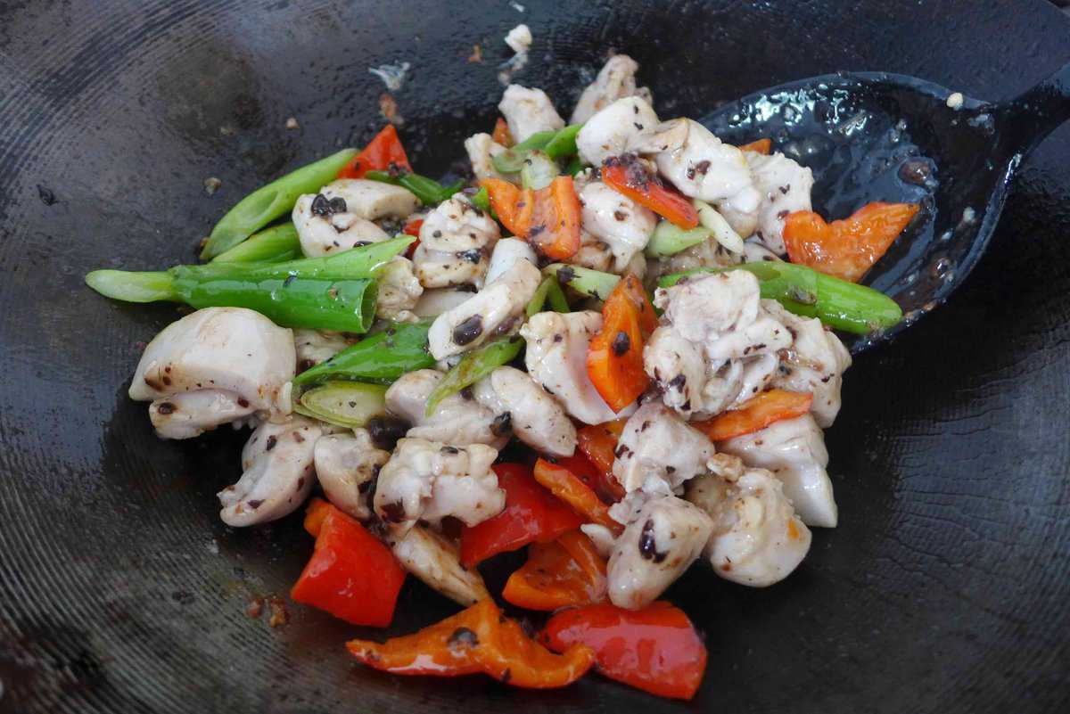stir-frying chicken and vegetables with seasonings.