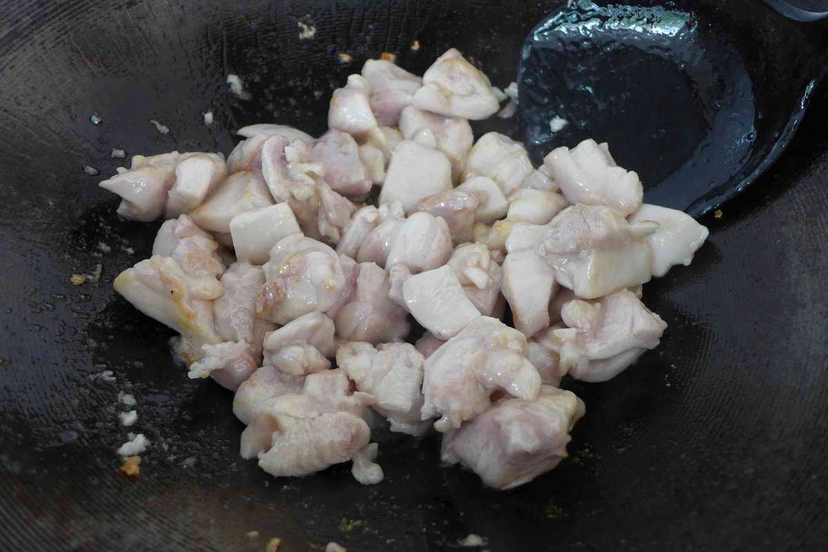 cooking chicken pieces in a wok.