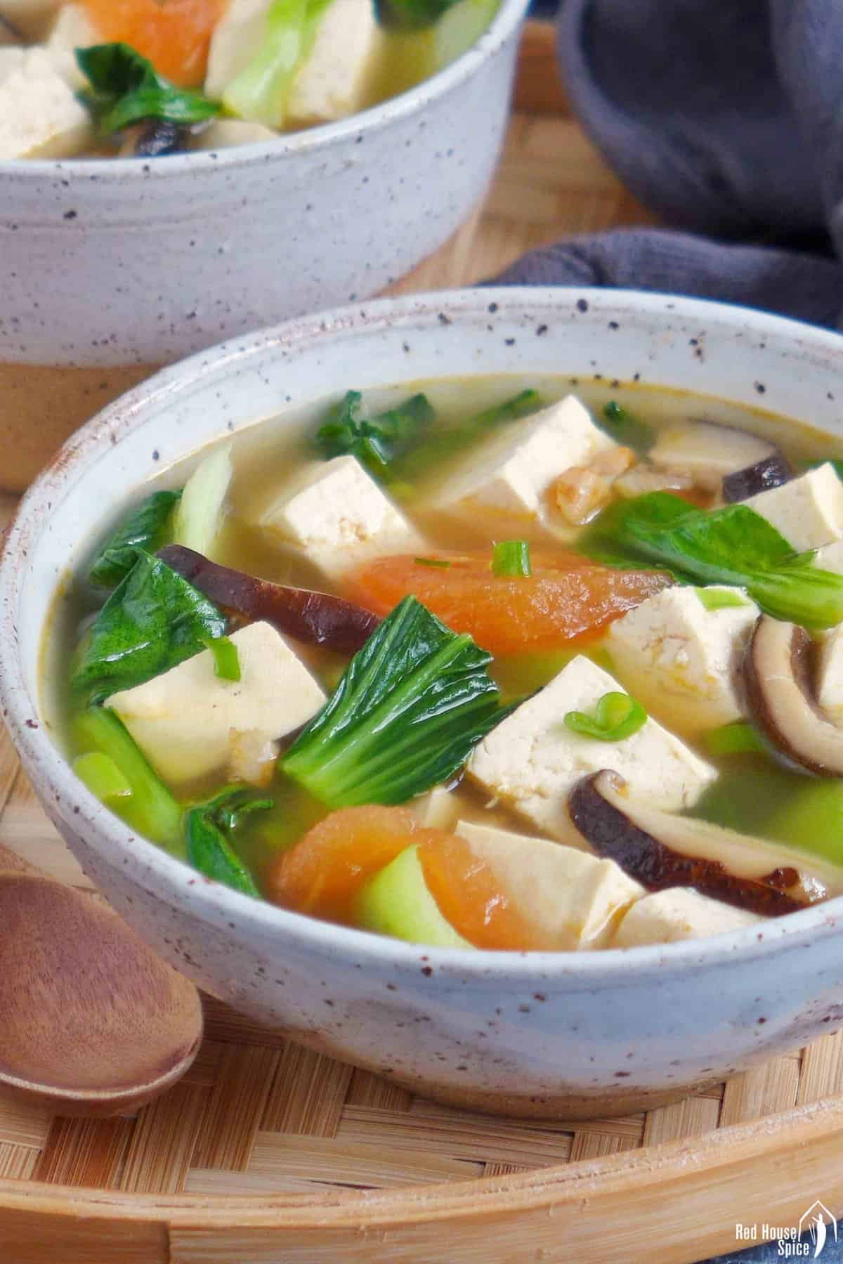 a bowl of tofu soup with vegetables .