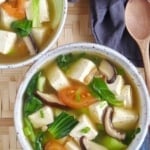 Two bowls of tofu soup with vegetables.