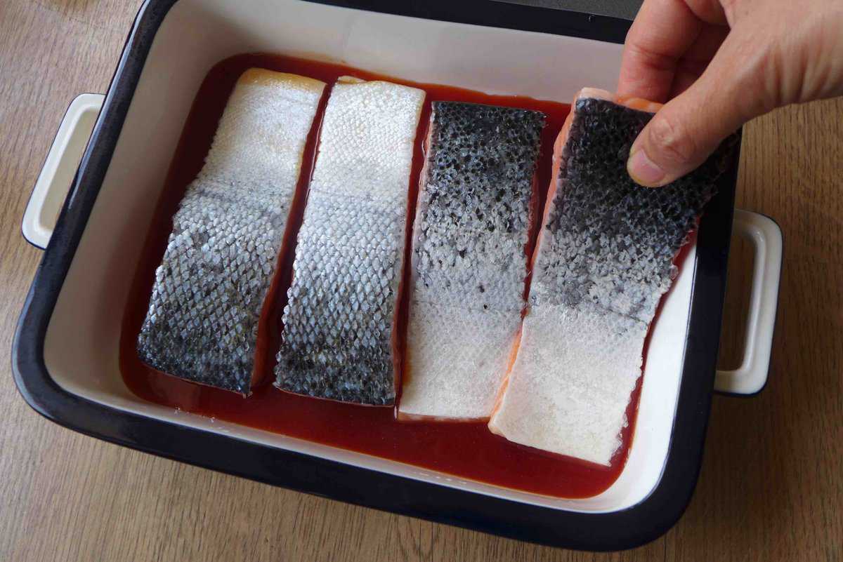 putting raw salmon into sweet and sour sauce.