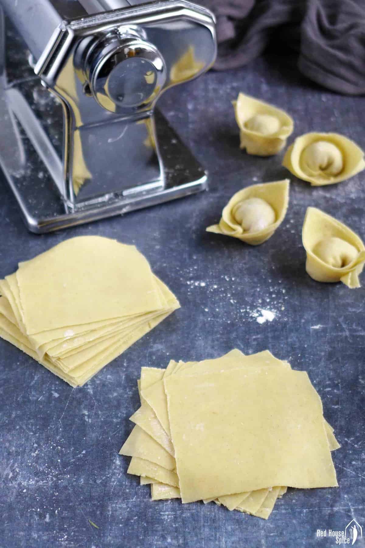 wonton wrappers with stuffed wontons and a pasta machine.