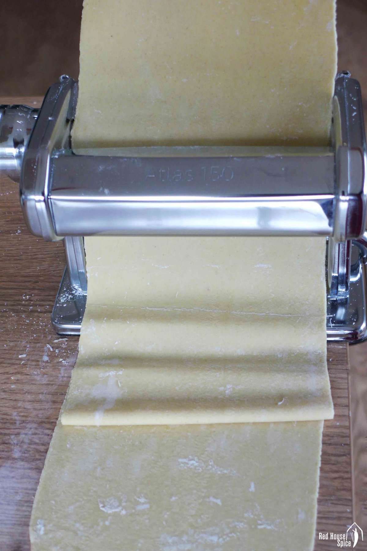 Rolling a sheet of dough with a pasta maker.