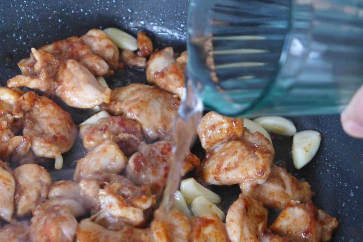 adding water to pan-fried chicken.