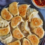 A plate of pan-fried dumplings with overlay text that says kimchi dumplings.
