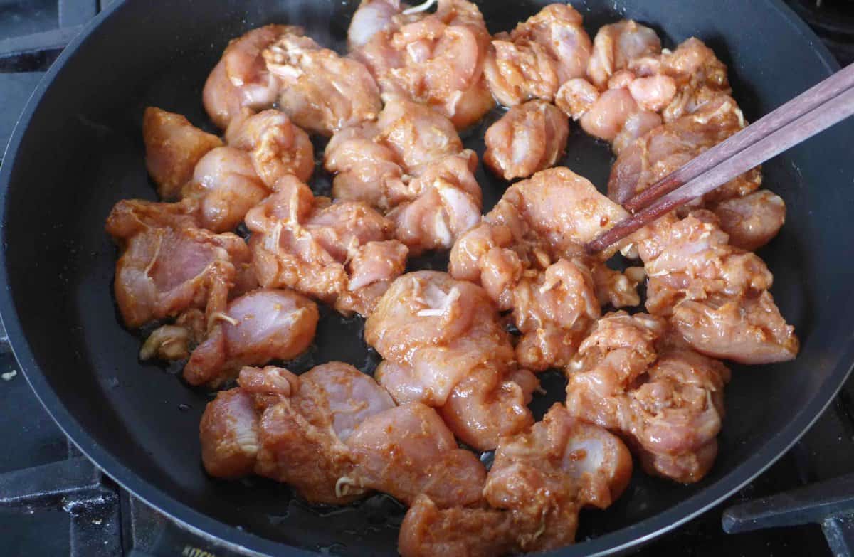 putting marinated chicken into a skillet.