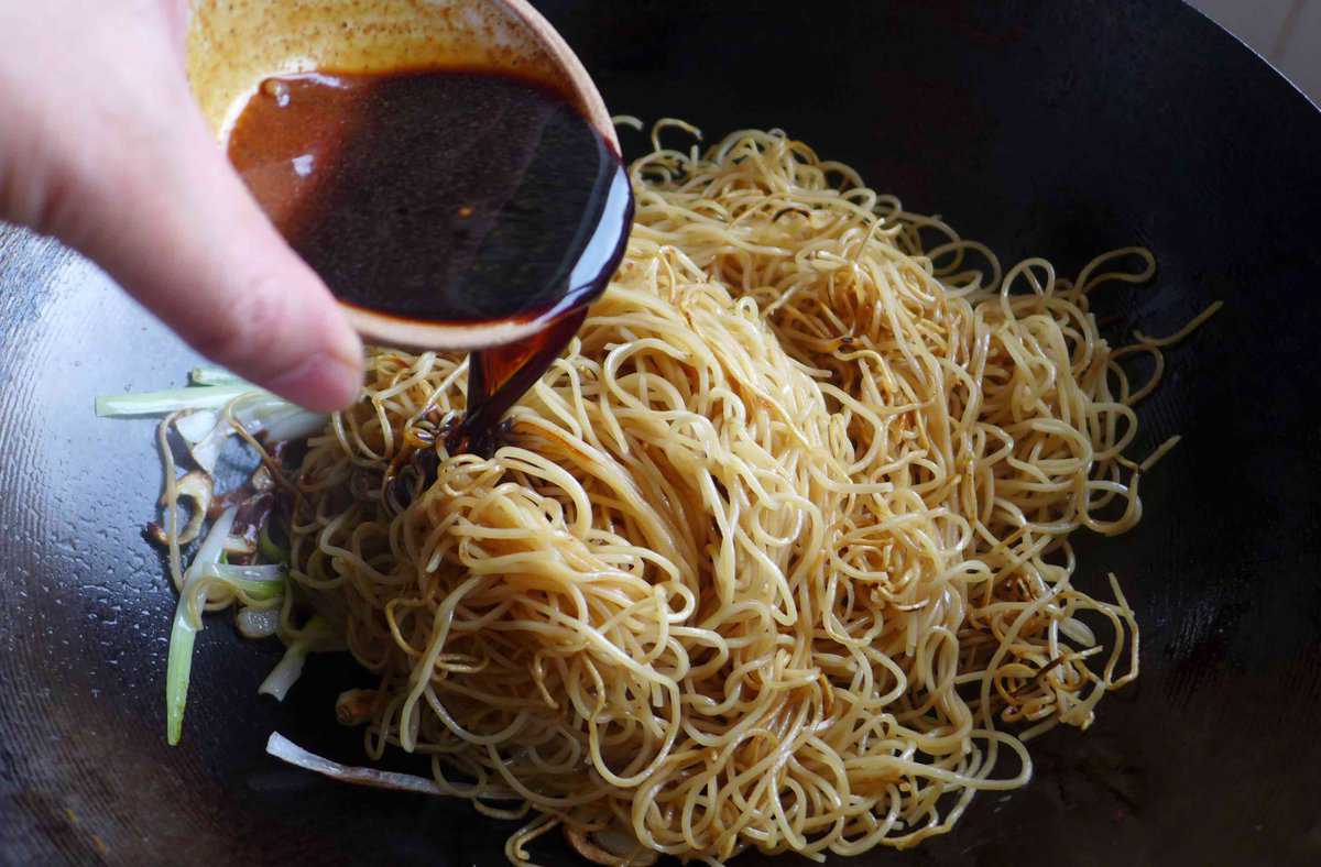 adding sauce to noodles.