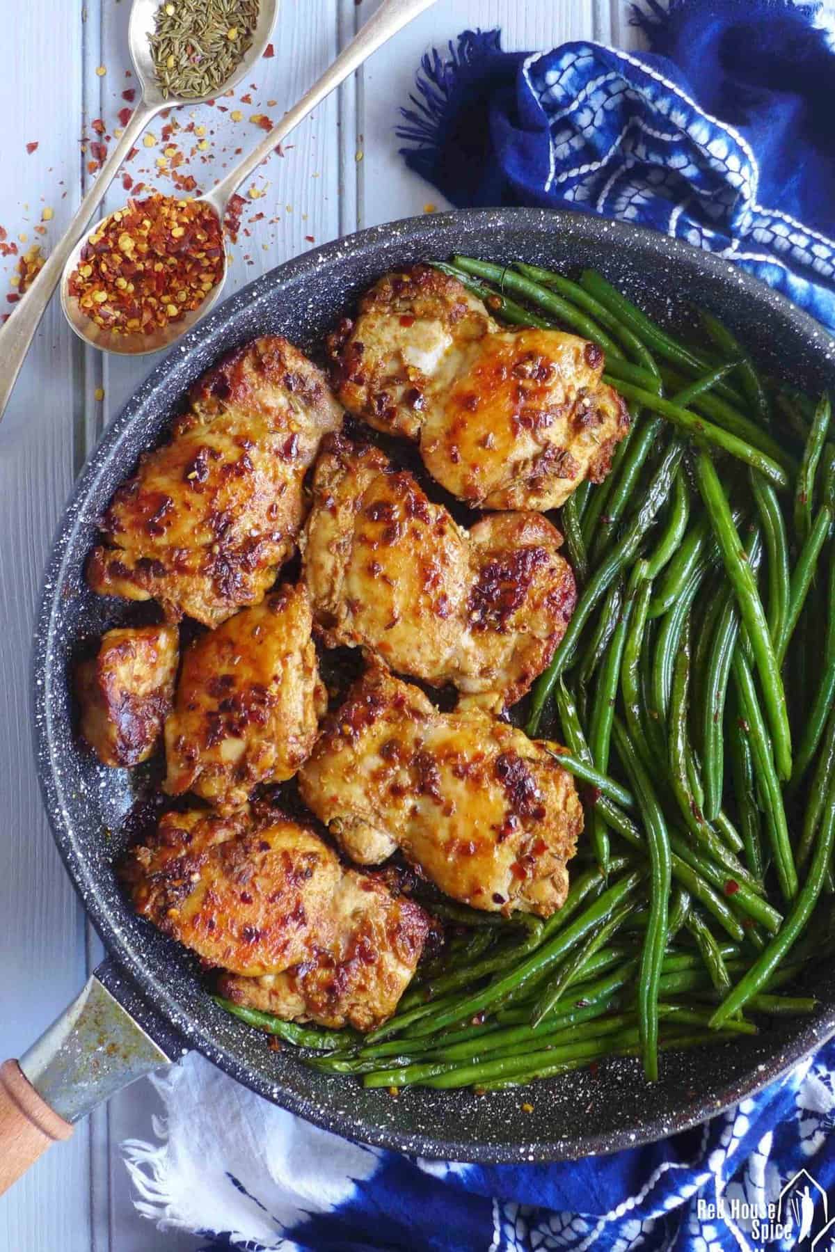 chili cumin chicken thighs and green beans in a skillet.