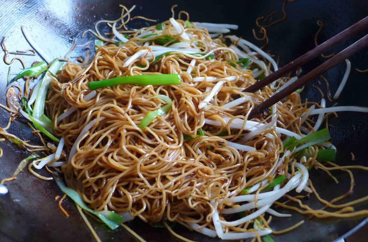 stir-frying noodles with scallions and bean sprouts.