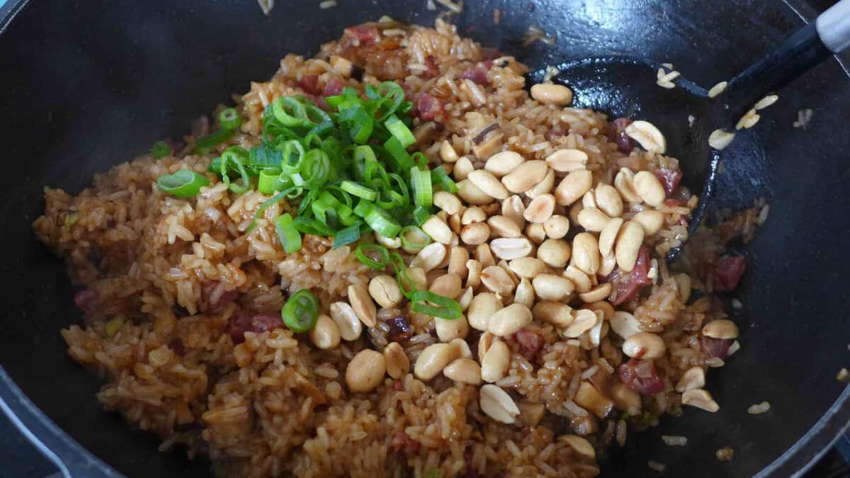 adding roasted peanuts and scallions to cooked sticky rice.