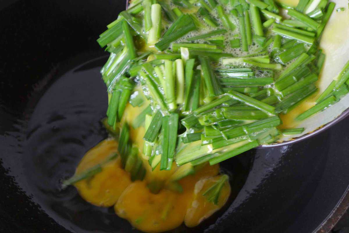 pouring egg and chive mixture to a wok.