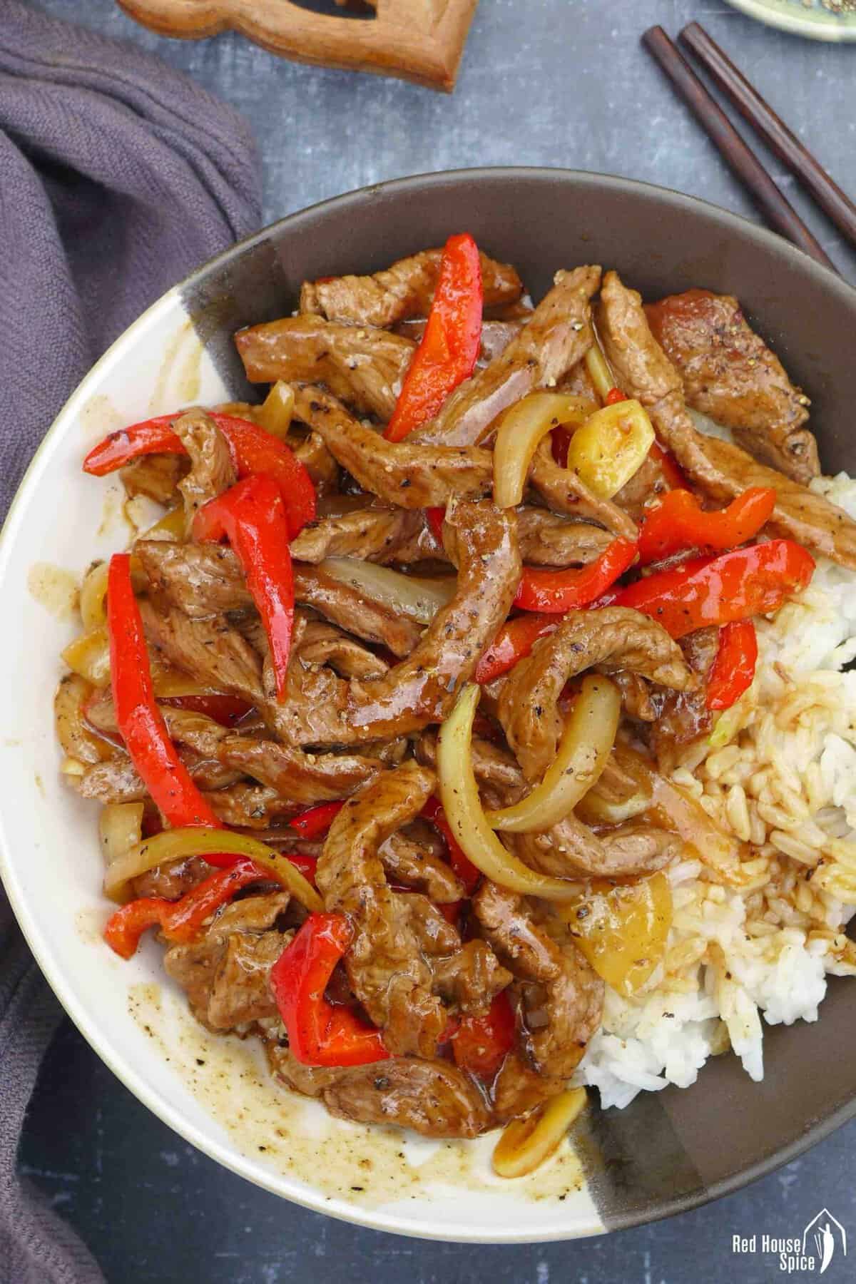black pepper beef stir-fry over a bowl of rice.