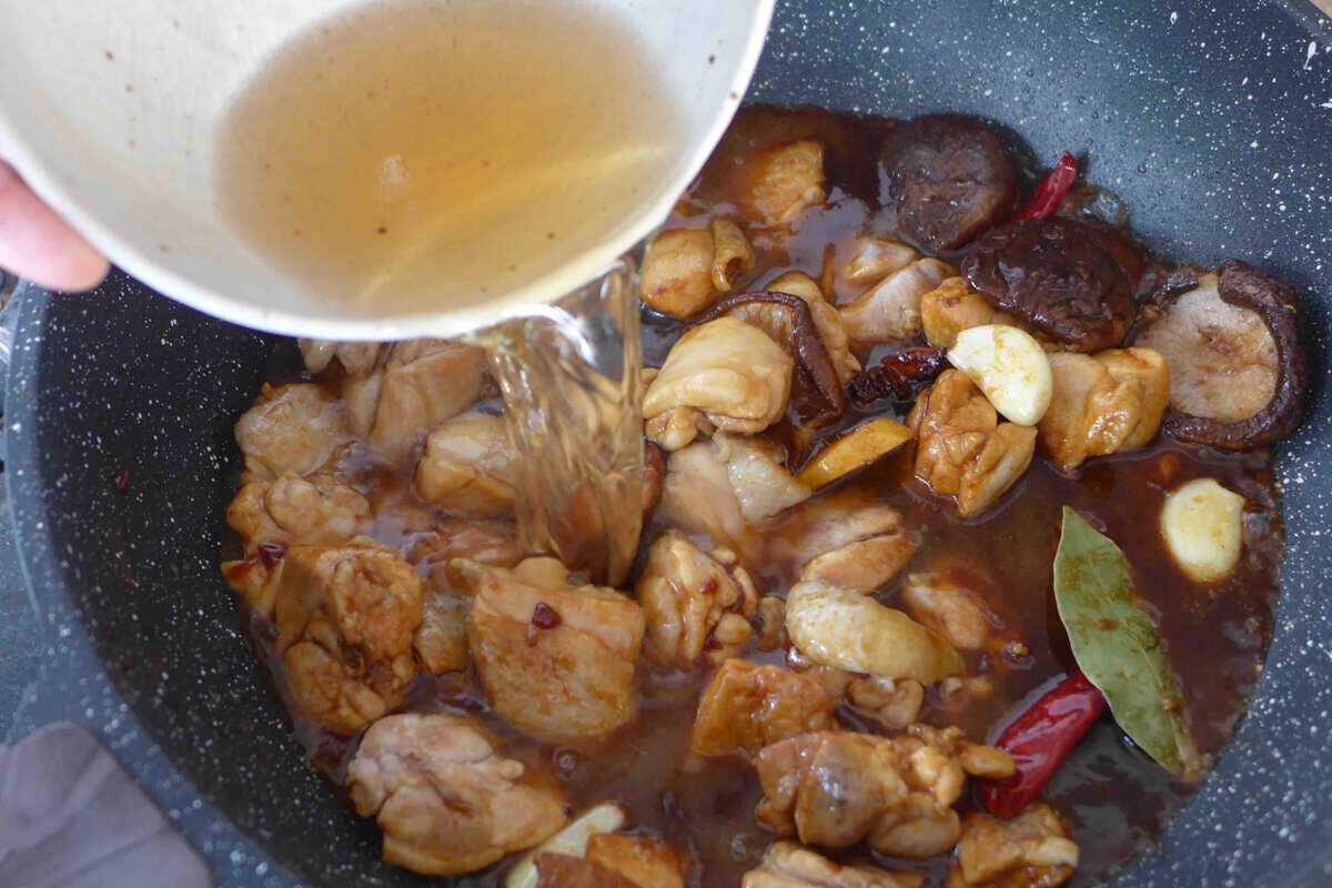 pouring mushroom soaking water over the chicken.
